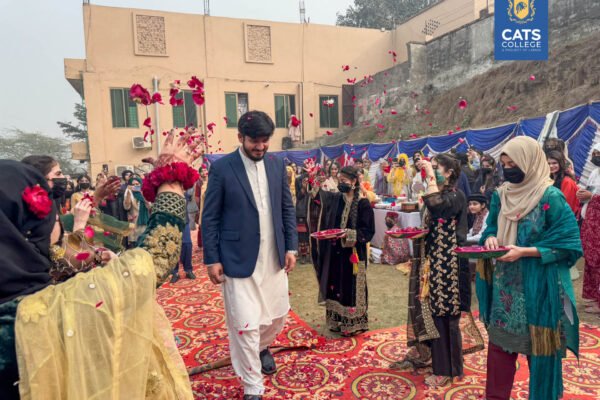Vibrant student activities at an intermediate college in Lahore featuring traditional dance performances in a decorated campus hall.