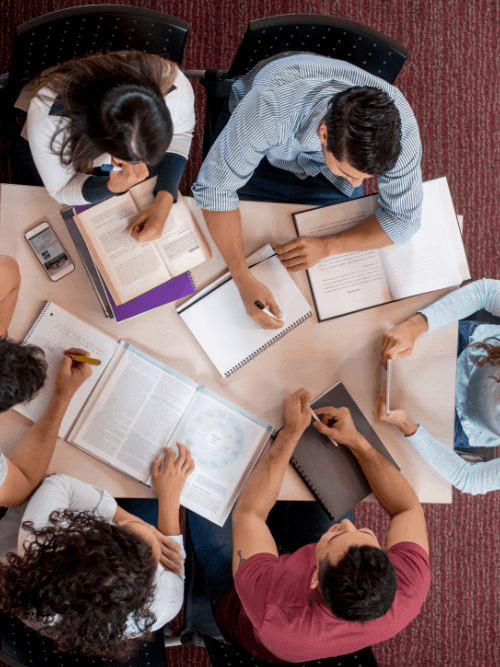 CATS students studying together in a group around a table with books and notebooks